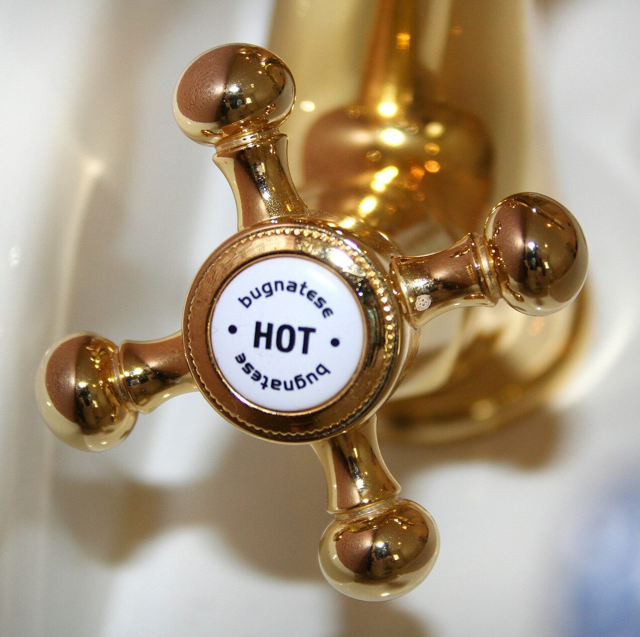 A gold faucet handle with the word HOT on a white label on the One Stop Plumbing water heater page