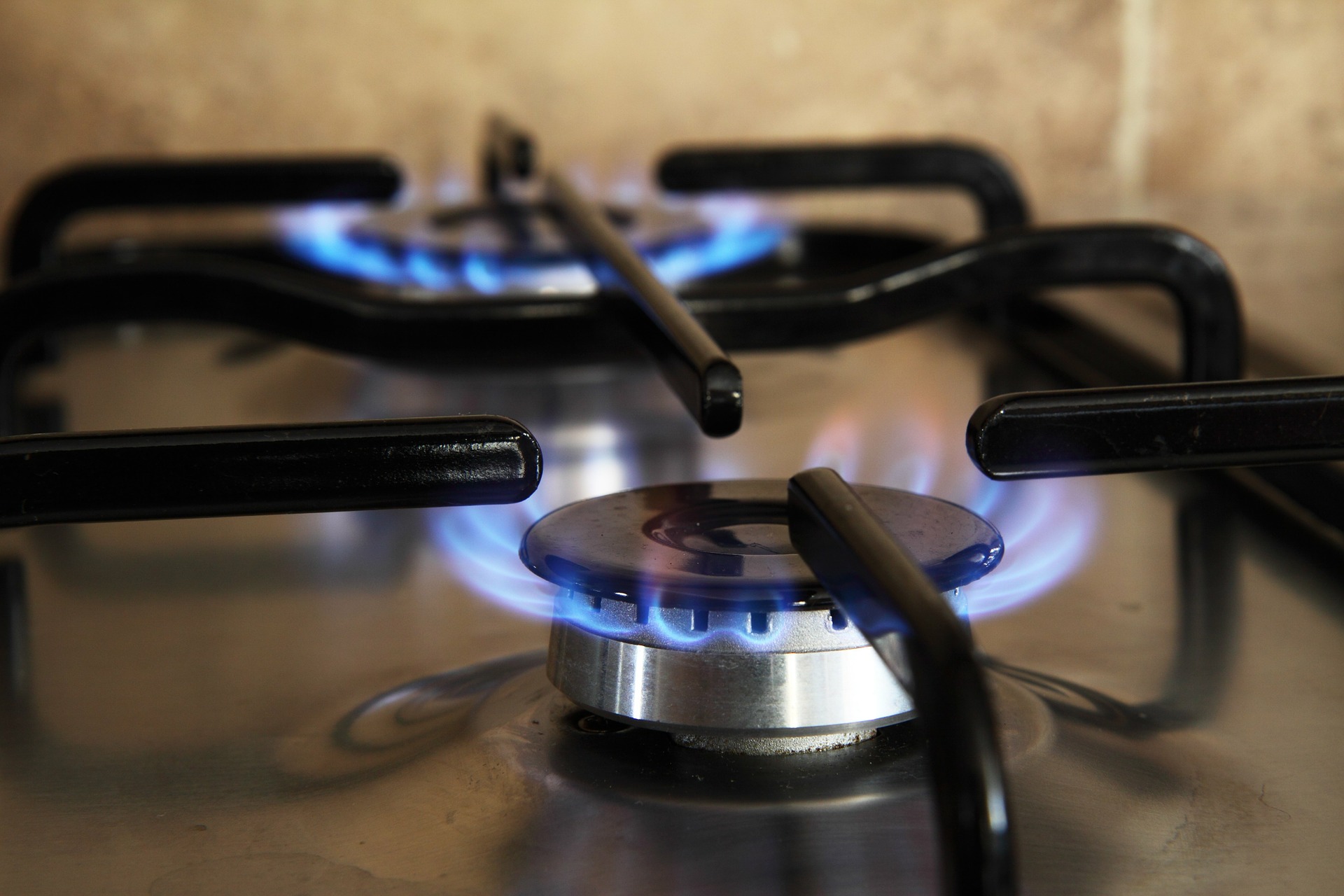 A gas appliance burner turned on in a black stovetop on the One Stop Plumbing gas appliances page
