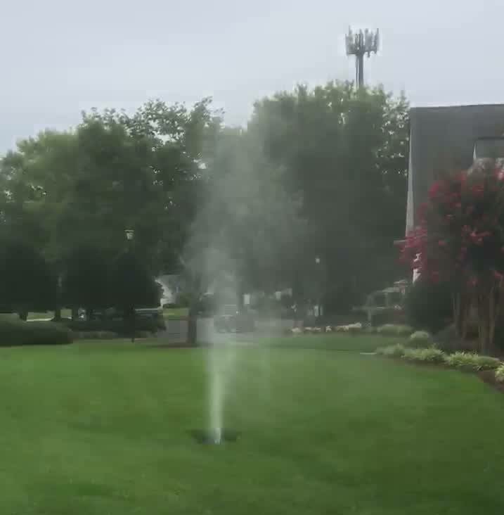 Water shooting up out of a hole in the ground with green grass and trees on the One Stop Plumbing Water Jetting page