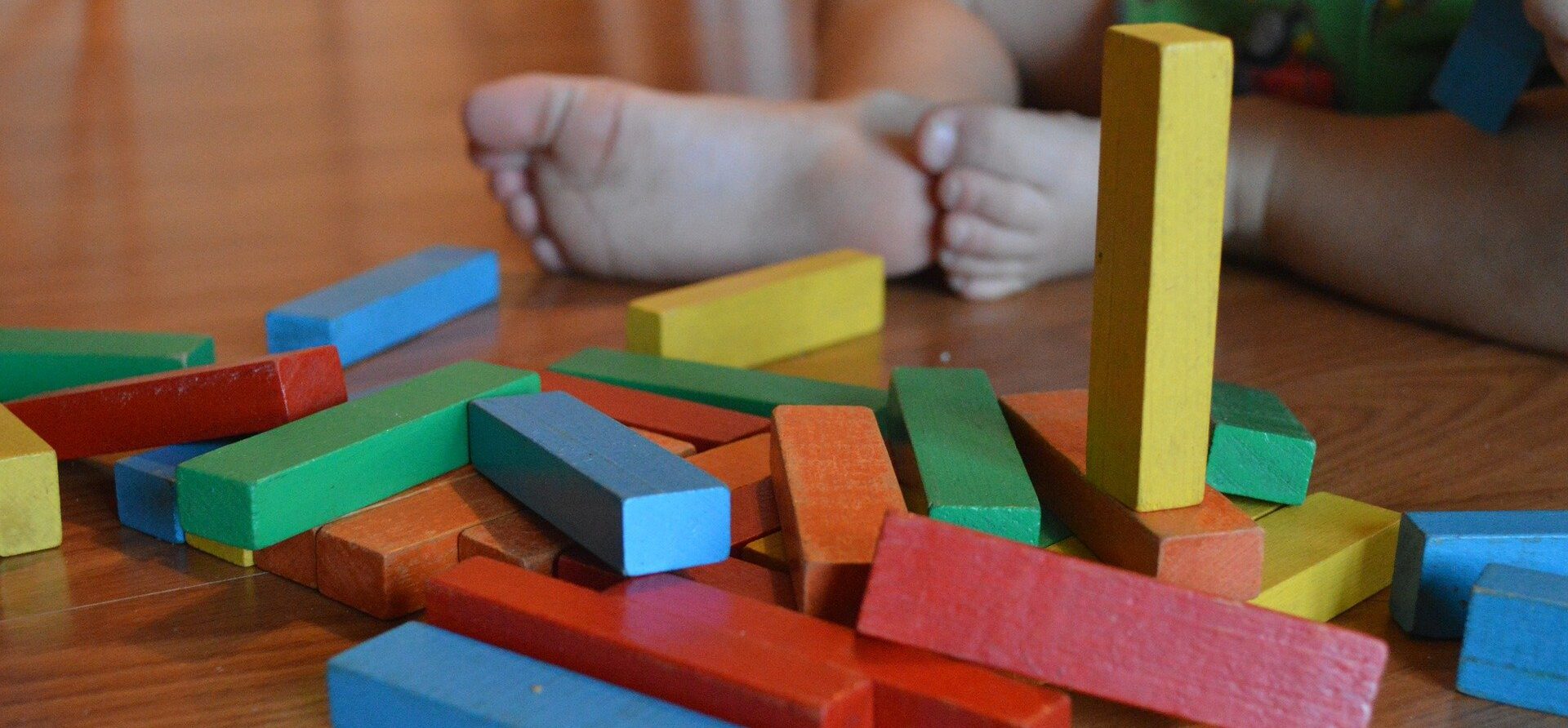 Small child playing on the floor with colorful blocks