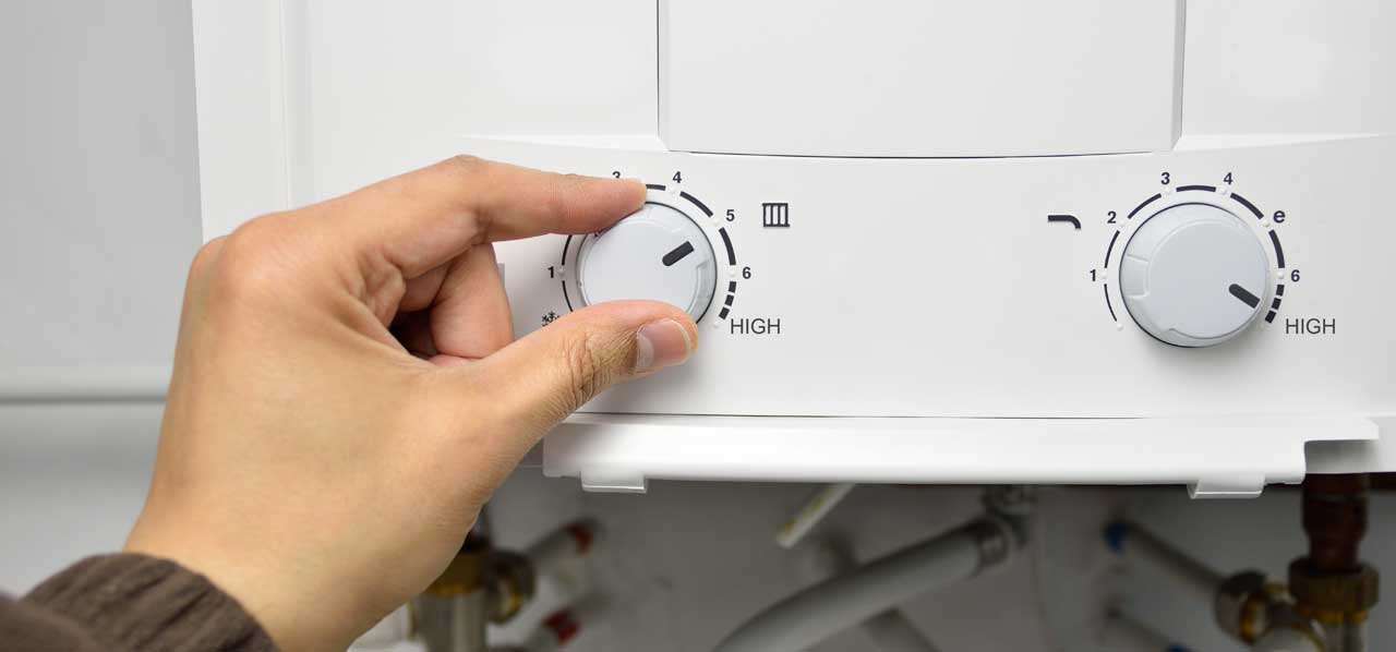 A person adjusting the water heater temperature during maintenance
