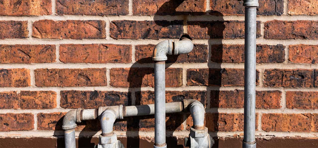 Brick wall with plumbing pipes entering the brick